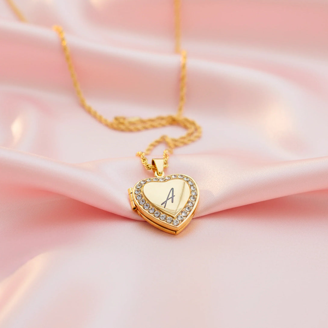 Gold heart-shaped locket necklace with crystals on pink silk backdrop